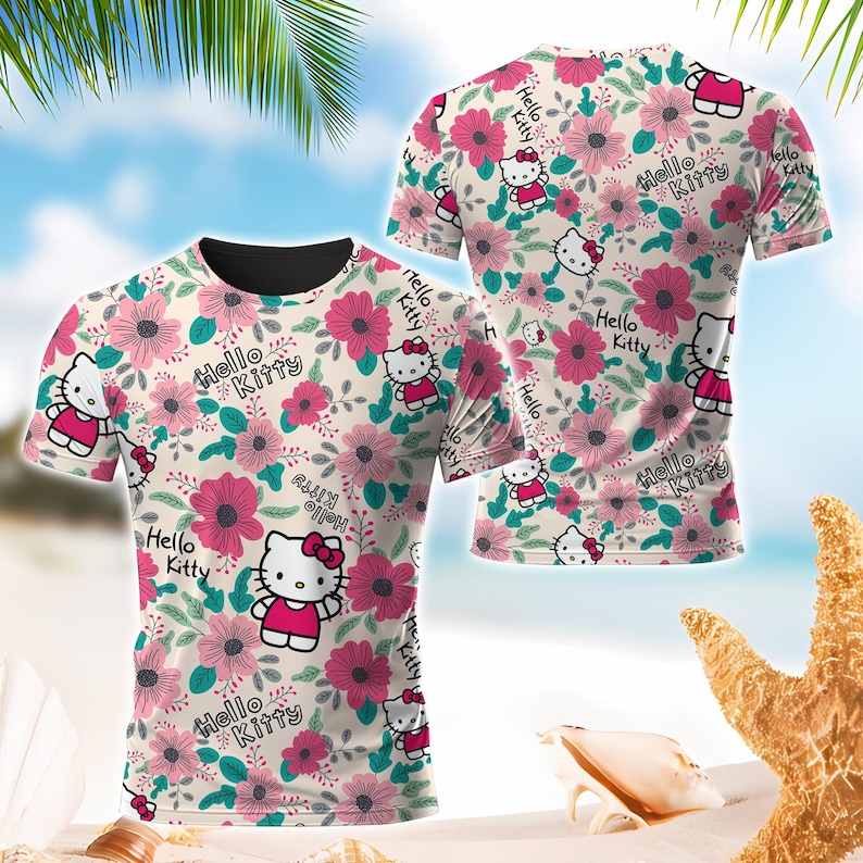 May include: A short-sleeved t-shirt featuring a floral pattern with pink flowers, green leaves, and the Hello Kitty character. The shirt has a cream-colored background and the words "Hello Kitty" are printed throughout the design.