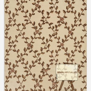 May include: Beige rug featuring a repeating pattern of brown vines, leaves, and pink flowers. The rug has a detailed, textured design. The text "IBRAHIMCARPETGALLERY" is visible on a small sign.
