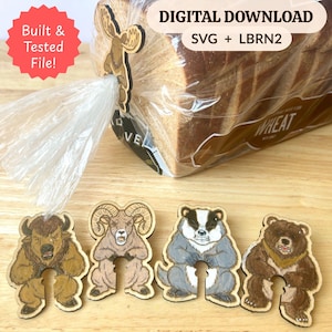 May include: A set of wooden bread clips featuring illustrations of a moose, bison, ram, badger, and bear. The moose clip is attached to a plastic bread bag. Text on the image reads: Built & Tested File! DIGITAL DOWNLOAD SVG + LBRN2.