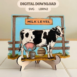 May include: A wooden sign featuring a black and white cow illustration with the text "MILK LEVEL" and "CEREAL HEAVEN". The sign is supported by a wooden stand. The background is light blue with a wooden fence design. The words "DIGITAL DOWNLOAD" and "SVG LBRN2" are at the top.