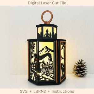 May include: A hexagonal lantern featuring black laser-cut panels with a steam train, mountain, and forest silhouette. The lantern has a circular top handle and emits a warm yellow light from within. Text reads Digital Laser Cut File.