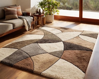 Può includere: Un tappeto rettangolare con un motivo geometrico nei toni del marrone, beige e grigio. Il tappeto presenta forme curve e angolari, creando un design moderno. Il tappeto è posato su un pavimento in legno.