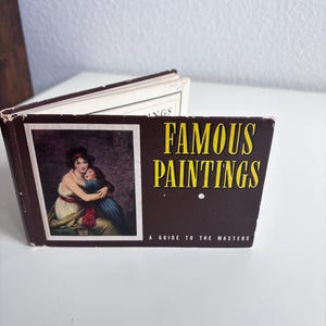 May include: A small, rectangular book titled Famous Paintings: A Guide to the Masters. The dark brown cover features a reproduction of a painting showing two figures embracing, with yellow text and a white subtitle on the front.