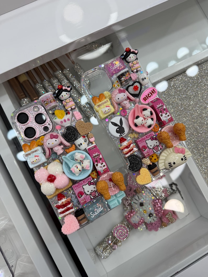 Pu&ograve; includere: Custodia per telefono trasparente decorata con vari ciondoli 3D, tra cui personaggi di Hello Kitty, dessert e la scritta "RICH!". La custodia presenta anche un cinturino da polso tempestato di gioielli, il tutto in un cassetto bianco.