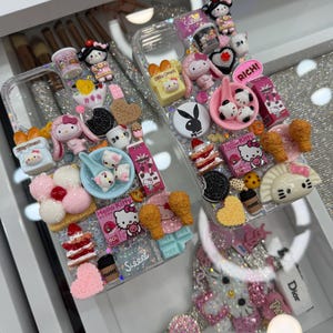 Pu&ograve; includere: Custodie trasparenti per telefono decorate con vari ciondoli 3D, tra cui personaggi di Hello Kitty, cibi in miniatura e la parola "Sweet". Le custodie sono impreziosite da glitter e strass, creando un'estetica giocosa e decorativa.