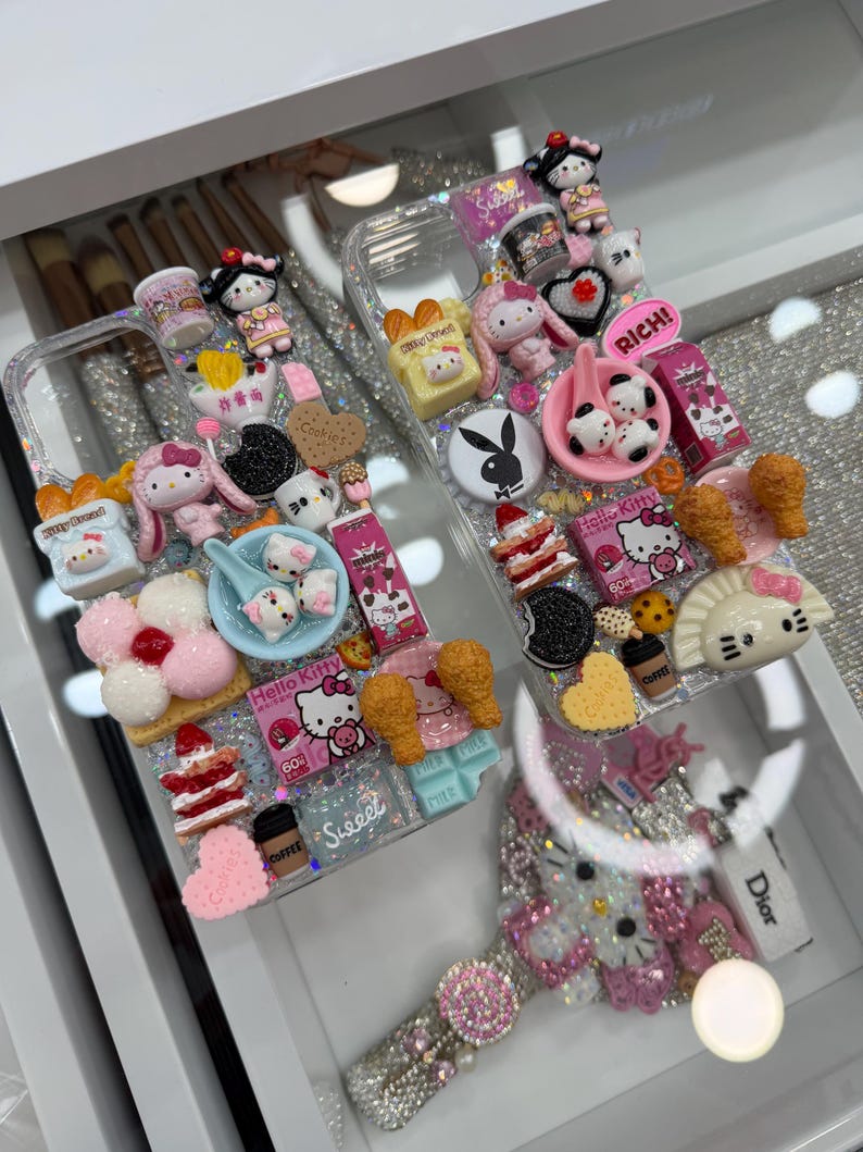 Pu&ograve; includere: Custodie trasparenti per telefono decorate con vari ciondoli 3D, tra cui personaggi di Hello Kitty, cibi in miniatura e la parola "Sweet". Le custodie sono impreziosite da glitter e strass, creando un'estetica giocosa e decorativa.