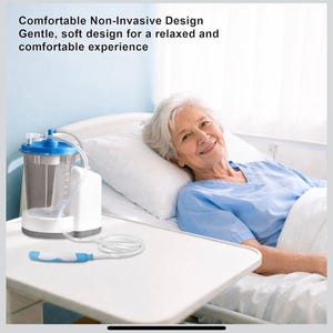 May include: A medical suction device with a clear canister, white base, and blue accents. The device is connected to a white tube and a blue and white handle. The text on the image reads: "Comfortable Non-Invasive Design Gentle, soft design for a relaxed and comfortable experience."