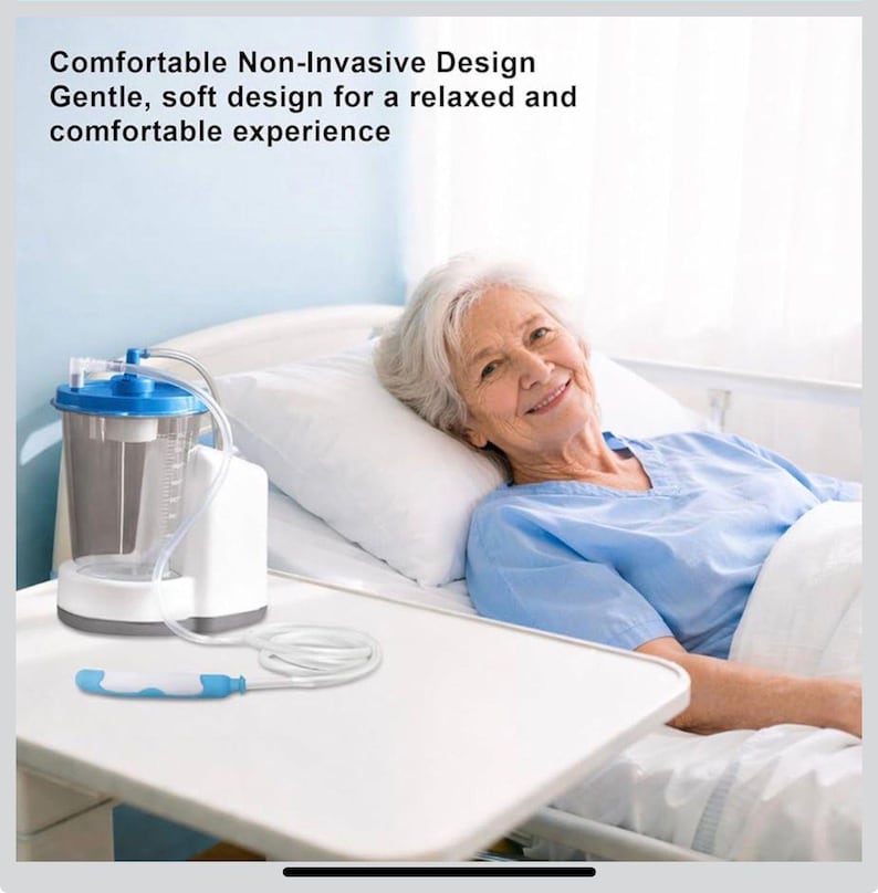 May include: A medical suction device with a clear canister, white base, and blue accents. The device is connected to a white tube and a blue and white handle. The text on the image reads: "Comfortable Non-Invasive Design Gentle, soft design for a relaxed and comfortable experience."