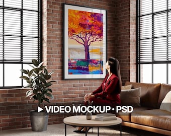 May include: A framed abstract tree painting with vibrant orange, purple, and yellow hues hangs on a brick wall. The artwork is above a round coffee table and a brown leather sofa. The text "VIDEO MOCKUP • PSD" is visible.