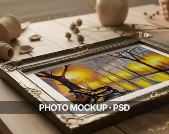 May include: An ornate, antique-style framed art print featuring a landscape painting with a bench, trees, and warm, glowing lights. The frame is dark with intricate detailing. Text at the bottom reads "PHOTO MOCKUP • PSD".