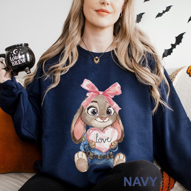 May include: Navy blue sweatshirt with a cartoon bunny holding a heart that says "Love". The bunny has a pink bow and a police uniform. The word "NAVY" is printed at the bottom of the sweatshirt.