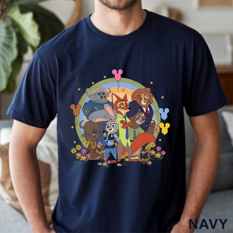 May include: Navy blue t-shirt featuring a colorful cartoon graphic of animal characters. The design includes a rainbow, flowers, and the word "NAVY" at the bottom. The shirt is a crew neck style.