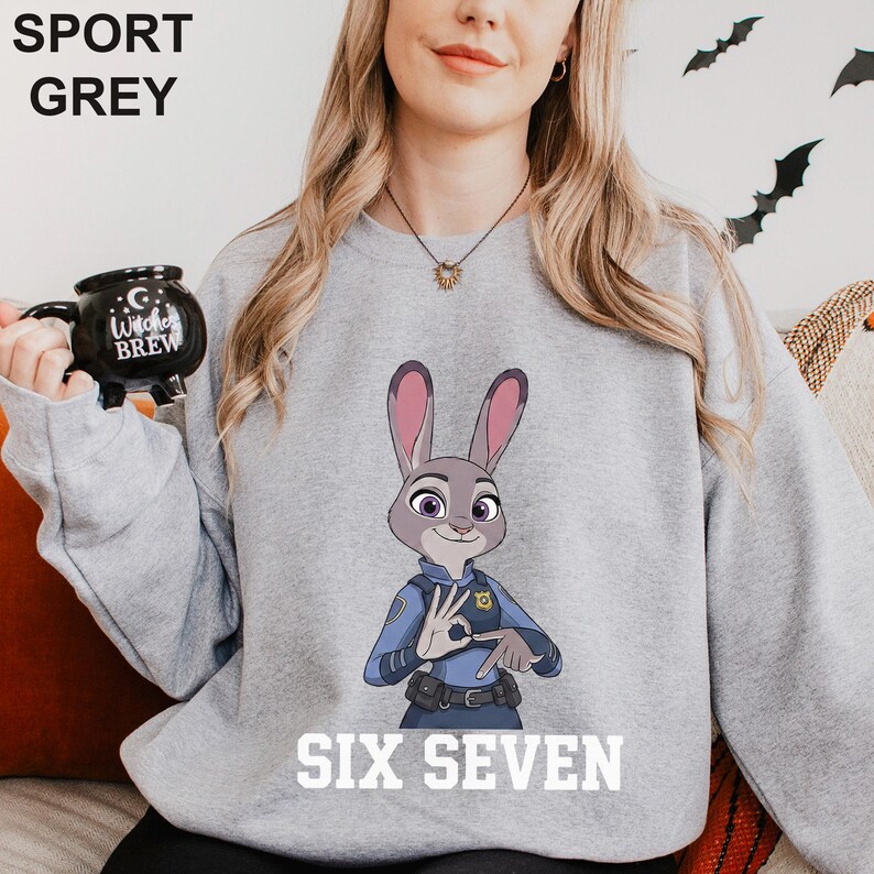 May include: Sport grey sweatshirt featuring a cartoon image of Judy Hopps from Zootopia in a police uniform. The text "SIX SEVEN" is printed in white at the bottom. The words "SPORT GREY" are printed in black at the top.