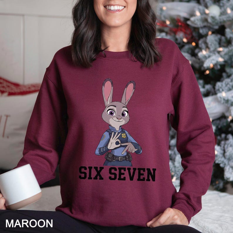 May include: Maroon sweatshirt featuring a cartoon image of a rabbit in a police uniform, with the text "SIX SEVEN" in black. The rabbit is making a hand gesture. The word "MAROON" is printed at the bottom.