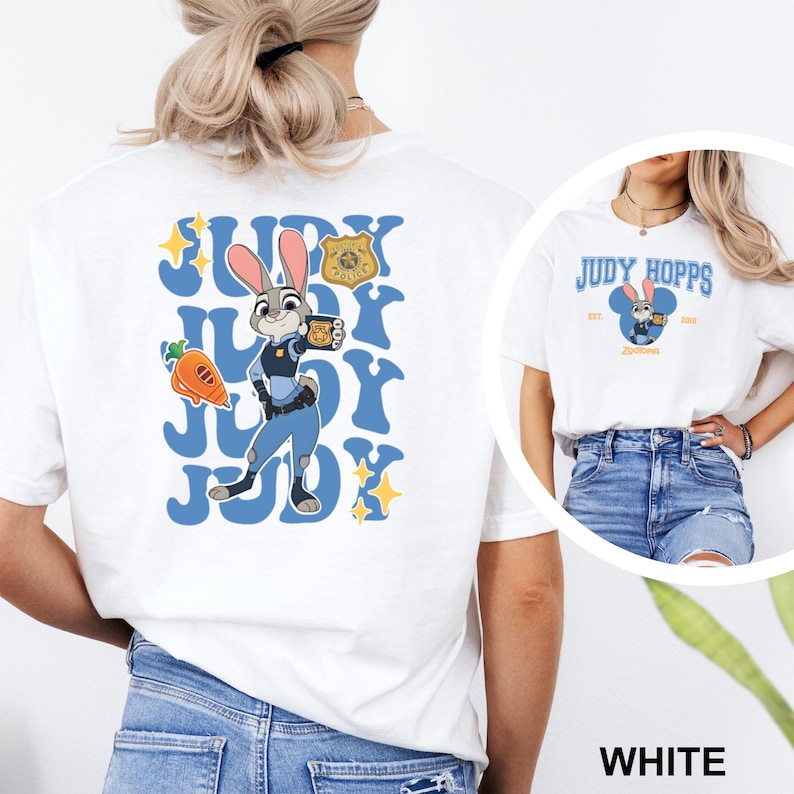 May include: White t-shirt featuring a cartoon image of Judy Hopps from Zootopia. The design includes the text "JUDY" in blue, a carrot, and a police badge. A smaller image of Judy Hopps is on the front.