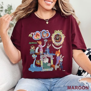 Puede incluir: Camiseta granate con un gr&aacute;fico colorido de personajes de la pel&iacute;cula animada "Zootopia". El dise&ntilde;o incluye retratos enmarcados y varios personajes de animales. La palabra "Zootopia" est&aacute; impresa en verde. La palabra "MAROON" est&aacute; impresa en la parte inferior.