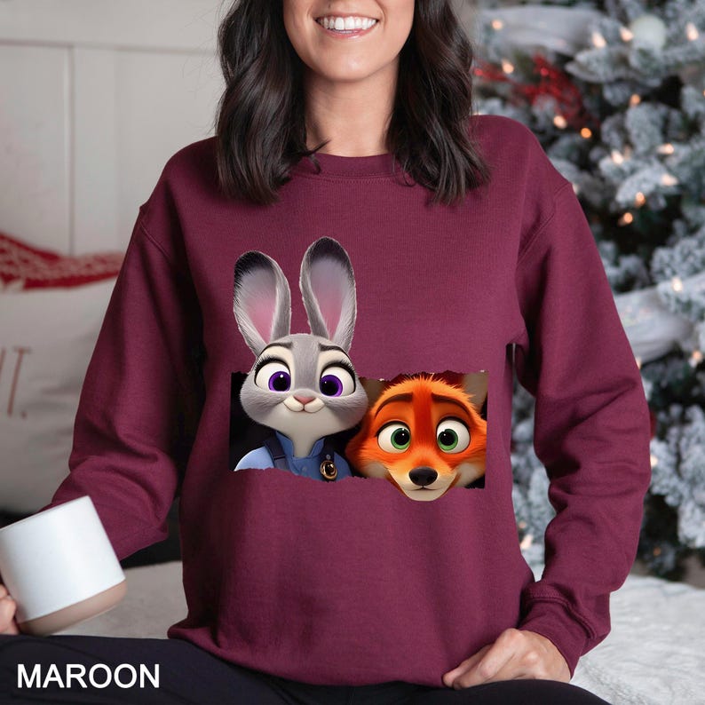 Może przedstawiać: Bordowa bluza z nadrukiem Judy Hopps i Nicka Wilde z filmu Zwierzogr&oacute;d. Bluza ma okrągły dekolt i długie rękawy. Słowo "MAROON" jest wydrukowane na dole.