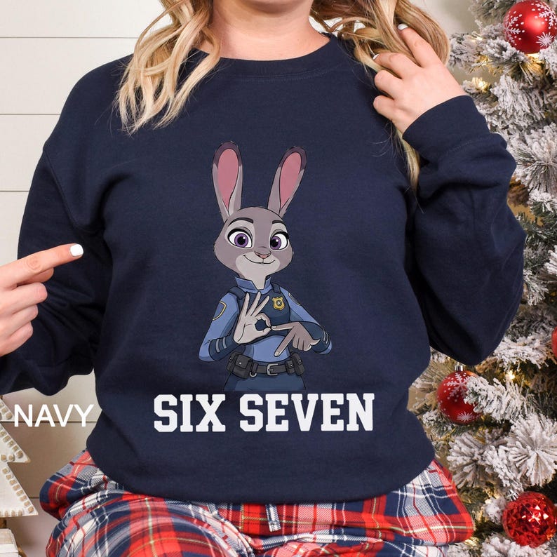 May include: Navy blue sweatshirt featuring a cartoon image of Judy Hopps from Zootopia, in a police uniform, making a hand gesture. The words "SIX SEVEN" are printed in white block letters below the image. The word "NAVY" is printed on the left side.