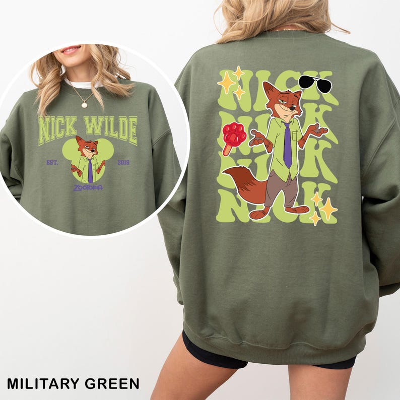 K&ouml;nnte beinhalten: Milit&auml;rgr&uuml;nes Sweatshirt mit einem Cartoon-Fuchscharakter mit Sonnenbrille und Lutscher. Auf der Vorderseite steht "NICK WILDE" und auf der R&uuml;ckseite der Name der Figur in einem sich wiederholenden Muster.