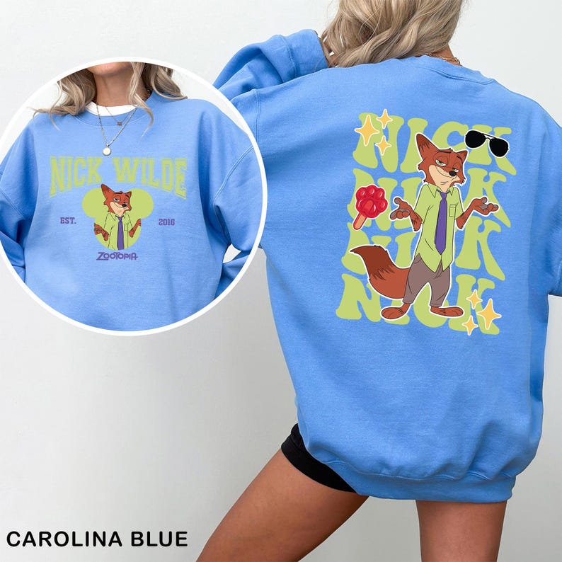 K&ouml;nnte beinhalten: Carolina-blaues Sweatshirt mit einem Cartoon-Fuchs-Charakter und dem Text "Nick Wilde". Auf der R&uuml;ckseite des Sweatshirts befindet sich ein Cartoon-Fuchs mit Sonnenbrille und dem Text "Nick Wilde". Die Vorderseite hat ein kreisf&ouml;rmiges Design.