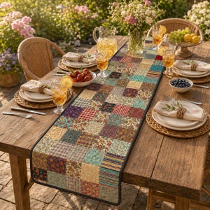 Könnte beinhalten: Ein rechteckiger, gesteppter Tischläufer mit einem Patchwork-Design aus verschiedenen floralen, karierten und geometrischen Stoffquadraten in Rot-, Blau-, Gelb- und Grüntönen. Der Läufer liegt mittig auf einem Holztisch mit Tellern und Gläsern.
