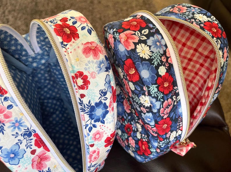Puede incluir: Dos bolsas en forma de coraz&oacute;n abiertas, con estampados florales. Una bolsa tiene un fondo blanco con flores rojas, rosas y azules, y un interior de lunares azules. La otra tiene un fondo azul marino con flores rojas y rosas y un interior de cuadros vichy rojos y blancos.