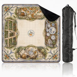 May include: A square outdoor blanket featuring a cream-colored center with a bird and orange motif, surrounded by a border of garden scenes, fruit trees, and blue and white patterned tableware. The blanket has a black underside and a black carrying bag.