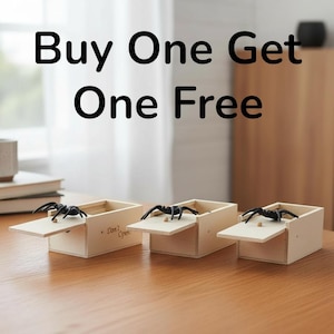 Puede incluir: Tres pequeñas cajas de madera con tapas con bisagras, cada una con una araña negra encima. Las cajas están sobre una superficie de madera. El texto "Buy One Get One Free" se muestra encima de las cajas.