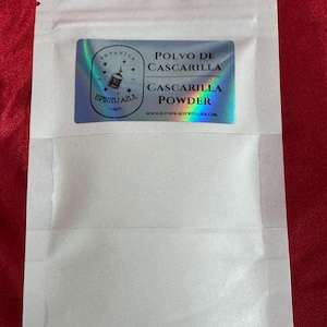 May include: A white, resealable pouch with a holographic label. The label reads "Polvo de Cascarilla" and "Cascarilla Powder" with the website address. The pouch is on a red surface.