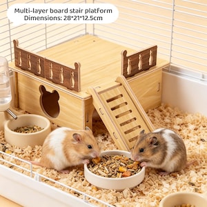 May include: A multi-layer wooden hamster habitat with a stair platform, measuring 28cm x 21cm x 12.5cm. The habitat includes a house, a ladder, and a food bowl. Two hamsters are eating from a bowl filled with food. The cage has a water bottle.