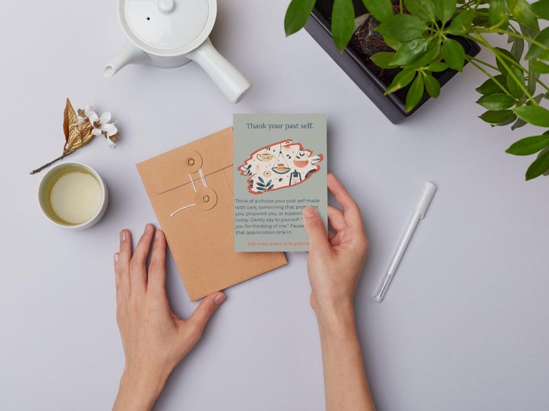 May include: A rectangular card with a gray background features the text Thank your past self at the top, followed by a central illustration of a hanging plant and botanical motifs, and a paragraph of text ending with And treat yourself with grace.