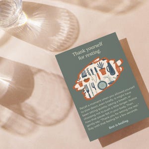 May include: A rectangular greeting card with a sage green background featuring the text Thank yourself for resting. A central orange brushstroke shape contains illustrations of kitchen utensils and plants. The bottom text reads Rest is healing.