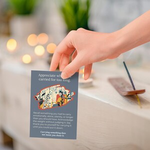 May include: A hand holding a grey card with text and a floral design. The card reads "Appreciate what you carried for too long." Incense and candles are in the background.