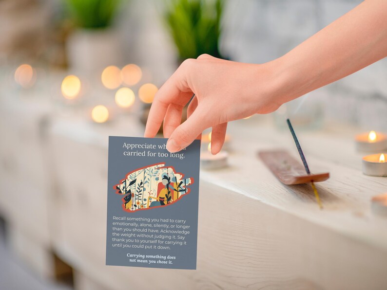 May include: A hand holding a grey card with text and a floral design. The card reads "Appreciate what you carried for too long." Incense and candles are in the background.