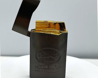 Encendedor vintage Jin Shi 1999 Proof con logo de león, tapa abatible en tono dorado, artículo de colección.