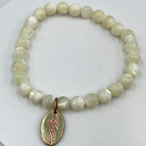 Vintage crèmekleurige stretcharmband met kralen en roze schriftbedel, minimalistisch boho