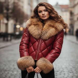 Puede incluir: Chaqueta de cuero acolchada burdeos con cuello y puños de piel. La chaqueta tiene cierre de cremallera y un patrón de diamantes. La piel es de color marrón claro. Prenda de abrigo elegante.