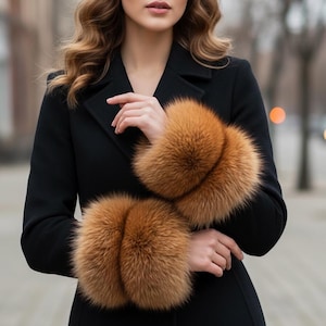 Puede incluir: Un abrigo negro con puños de piel de color marrón anaranjado. Los puños de piel contrastan con el abrigo oscuro, creando un look sofisticado y elegante. El abrigo es de estilo clásico, ideal para el invierno.