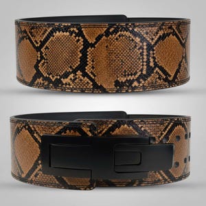Puede incluir: Un cinturón de halterofilia con un estampado de piel de serpiente en tonos marrón y negro. El cinturón tiene un cierre de hebilla negro y está diseñado para dar soporte durante ejercicios de levantamiento de pesas. El cinturón se muestra en dos vistas.