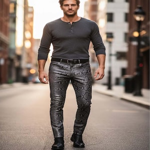 Op de afbeelding: Een persoon draagt een donkergrijs Henley-shirt met lange mouwen, een zwarte riem en een broek met slangenpatroon. De persoon draagt ook zwarte laarzen. De foto is genomen op een stadsstraat.