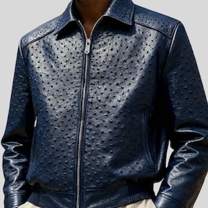 Può includere: Giacca in pelle blu navy con un motivo strutturato e puntinato. La giacca presenta un collo, una cerniera a tutta lunghezza e polsini e orlo a coste. La giacca ha un classico stile bomber.