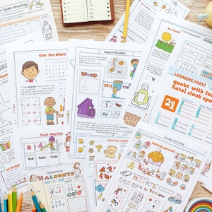 May include: A selection of illustrated educational worksheets with text, including the words "Learning Warrior" and "Goo lec diors." Pencils, a blue case, and a notebook are arranged around the papers, creating a learning scene.