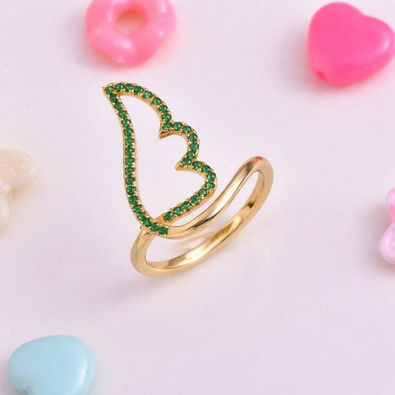 Angel wing ring with emerald-green CZ stones on a gold-tone split band; delicate boho everyday ring, perfect gift for her.