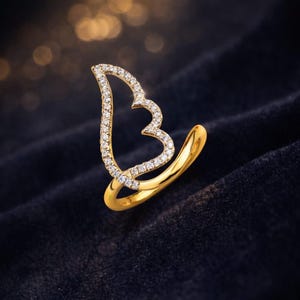 Gold-tone CZ angel wing ring with a crystal-studded outline and curved band on dark velvet backdrop, gift for her.