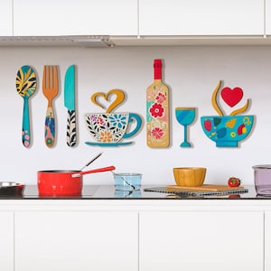 Könnte beinhalten: Bunte Küchendekoration aus Holz mit Löffel, Gabel, Messer, Teetasse, Weinflasche, Weinglas und Schüssel. Die Teetasse und die Weinflasche haben florale Designs. Die Schüssel hat ein Herz- und Dampfdesign.