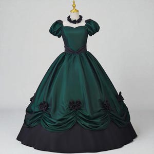 May include: A dark green ball gown with a black skirt and accents. The dress features a sweetheart neckline, short puffed sleeves, and a black ribbon belt. Black floral embellishments adorn the skirt, and a black choker necklace is included.