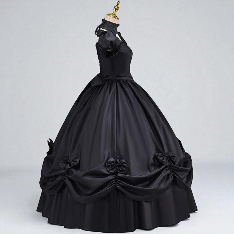 May include: A black ball gown with a high collar and short sleeves. The dress features a fitted bodice, a full skirt, and decorative bows. The gown is displayed on a mannequin against a plain background.