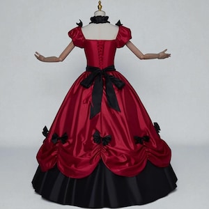 May include: A red and black ball gown with a square neckline and short, puffed sleeves. The bodice features a laced back and a black bow at the waist. The skirt is full, with black accents and bows.
