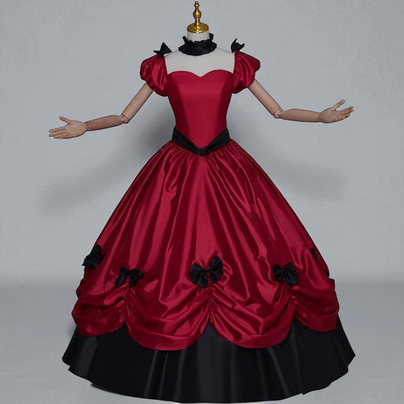 May include: A formal red gown with a black skirt and accents. The bodice features a sweetheart neckline and short, puffed sleeves. Black bows adorn the skirt. The dress is displayed on a mannequin.