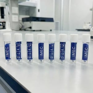Könnte beinhalten: Sieben transparente Fläschchen mit weißen Verschlüssen, gefüllt mit einer dunkelblauen Substanz. Die Fläschchen sind mit "IMEC" beschriftet und haben Volumenmarkierungen von 0,5 ml, 1,0 ml und 1,8 ml. Sie stehen auf einer weißen Oberfläche.